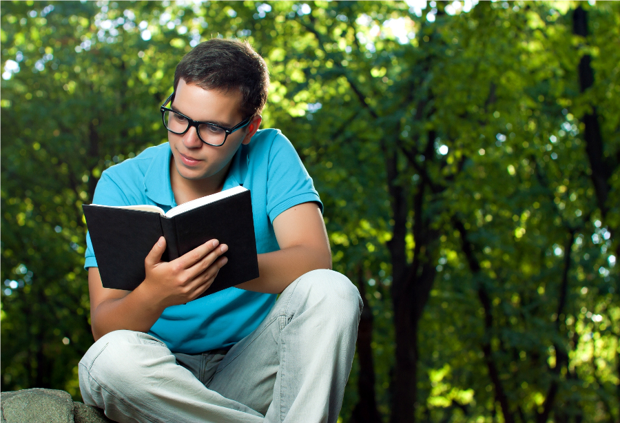 young man reading book in the park